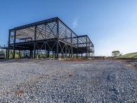 a picture of a building being built on a field near a forest in the background