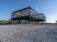 a picture of a building being built on a field near a forest in the background