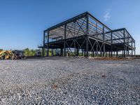 a picture of a building being built on a field near a forest in the background