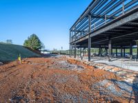 a picture of a building being built on a field near a forest in the background