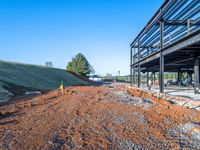 a picture of a building being built on a field near a forest in the background