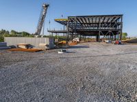 a picture of a building being built on a field near a forest in the background