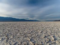 the empty dry desert is covered in sand and mountains in the distance's horizon