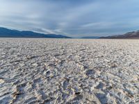 large vast expanse with white sand in the foreground with blue sky above it and distant mountains in the background