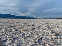 large vast expanse with white sand in the foreground with blue sky above it and distant mountains in the background