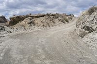 an empty road in the middle of some dirt and rocks on it is a gray color