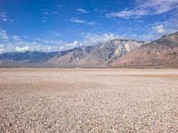 an empty desert with rocky ground, mountains in the distance and clouds in the sky