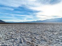 a person stands on a salt covered ground with a frisbee in hand while a view of mountains is in the distance