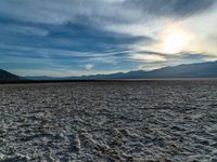 a person stands on a salt covered ground with a frisbee in hand while a view of mountains is in the distance