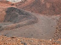 a man standing on a dirt road in front of a pile of dirt and rocks