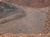 a man standing on a dirt road in front of a pile of dirt and rocks