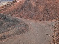 a man standing on a dirt road in front of a pile of dirt and rocks