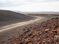 a large mound of dirt with many tracks in it and mountains in the background in the middle