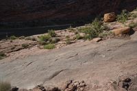 a man riding a horse in the desert by a river and rock face in background