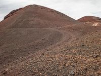 a person riding a horse on a mountainous area covered in dirt and rocks with hills in the background