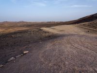 a truck on a dirt road in the desert with rocks and stones on the ground