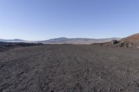 a motorcycle with it's tail tire extended stands in a barren landscape with a mountains in the distance