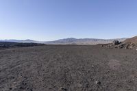 a motorcycle with it's tail tire extended stands in a barren landscape with a mountains in the distance