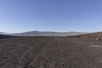 a motorcycle with it's tail tire extended stands in a barren landscape with a mountains in the distance