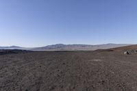 a motorcycle with it's tail tire extended stands in a barren landscape with a mountains in the distance