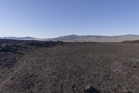 a motorcycle with it's tail tire extended stands in a barren landscape with a mountains in the distance