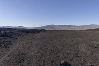 a motorcycle with it's tail tire extended stands in a barren landscape with a mountains in the distance