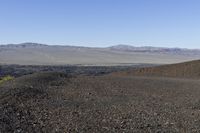 a motorcycle with it's tail tire extended stands in a barren landscape with a mountains in the distance