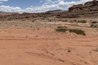 a desert scene with a man riding a motorcycle down it's side road in the desert