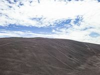 a person riding on a motorcycle through a pile of sand and rocks next to a mountain