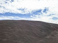 a person riding on a motorcycle through a pile of sand and rocks next to a mountain