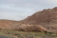 a motorcycle is driving along the road in the desert landscape with large rocks in the background