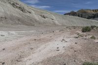 a person is riding a small motorcycle in the desert looking at a mountain pass with dirt and rocks