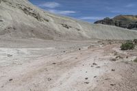 a person is riding a small motorcycle in the desert looking at a mountain pass with dirt and rocks