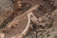 a person rides on the bike next to a steep hill in the desert, where many rocks are sticking out