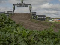 a man on a motorcycle jumping over the top of a dirt course at a monster track