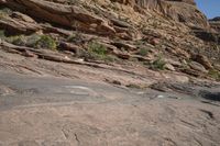 a person on a skateboard in the middle of a rocky area near a steep cliff