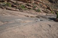 a person on a skateboard in the middle of a rocky area near a steep cliff