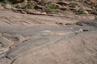 a person on a skateboard in the middle of a rocky area near a steep cliff