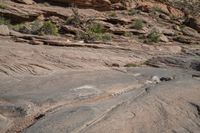 a person on a skateboard in the middle of a rocky area near a steep cliff