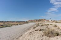 road leading to a small, sandy area with mountains in the background in an arid land