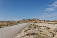 road leading to a small, sandy area with mountains in the background in an arid land