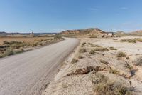 road leading to a small, sandy area with mountains in the background in an arid land