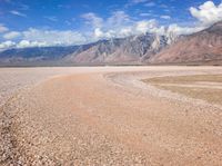 a barren desert is shown with mountains in the background and some clouds in the sky