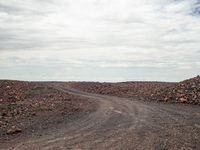 a person is riding a bicycle on a dirt road with rocky ground around it in the background