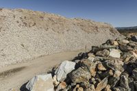 there is a bike rider on a paved dirt road through rocky area near a mountain