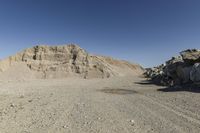 there is a bike rider on a paved dirt road through rocky area near a mountain