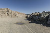 there is a bike rider on a paved dirt road through rocky area near a mountain