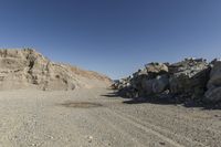 there is a bike rider on a paved dirt road through rocky area near a mountain