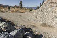 there is a bike rider on a paved dirt road through rocky area near a mountain