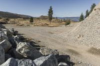 there is a bike rider on a paved dirt road through rocky area near a mountain